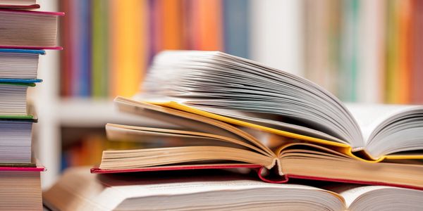Stack of open and closed books on a table.