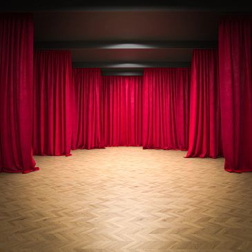Room with red curtains and wooden floor.