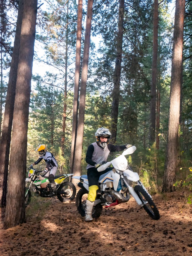 Man riding dirt bike in forest. Enduro motorcycle riders racing on forest path during outdoor sport training session. Offroad adventure travel and extreme recreational transport activity.