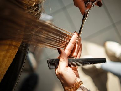 Hairdresser cutting a client's hair with scissors and comb.