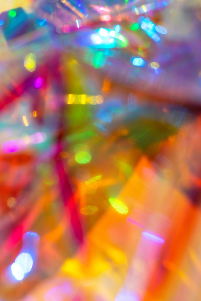 Vibrant holographic light and colorful bokeh creating a festive, glittering abstract background.