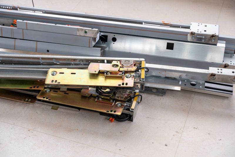 Elevator door mechanism components and steel tracks laid on concrete at a construction site, ready for installation or maintenance, symbolizing modern building technology and progress