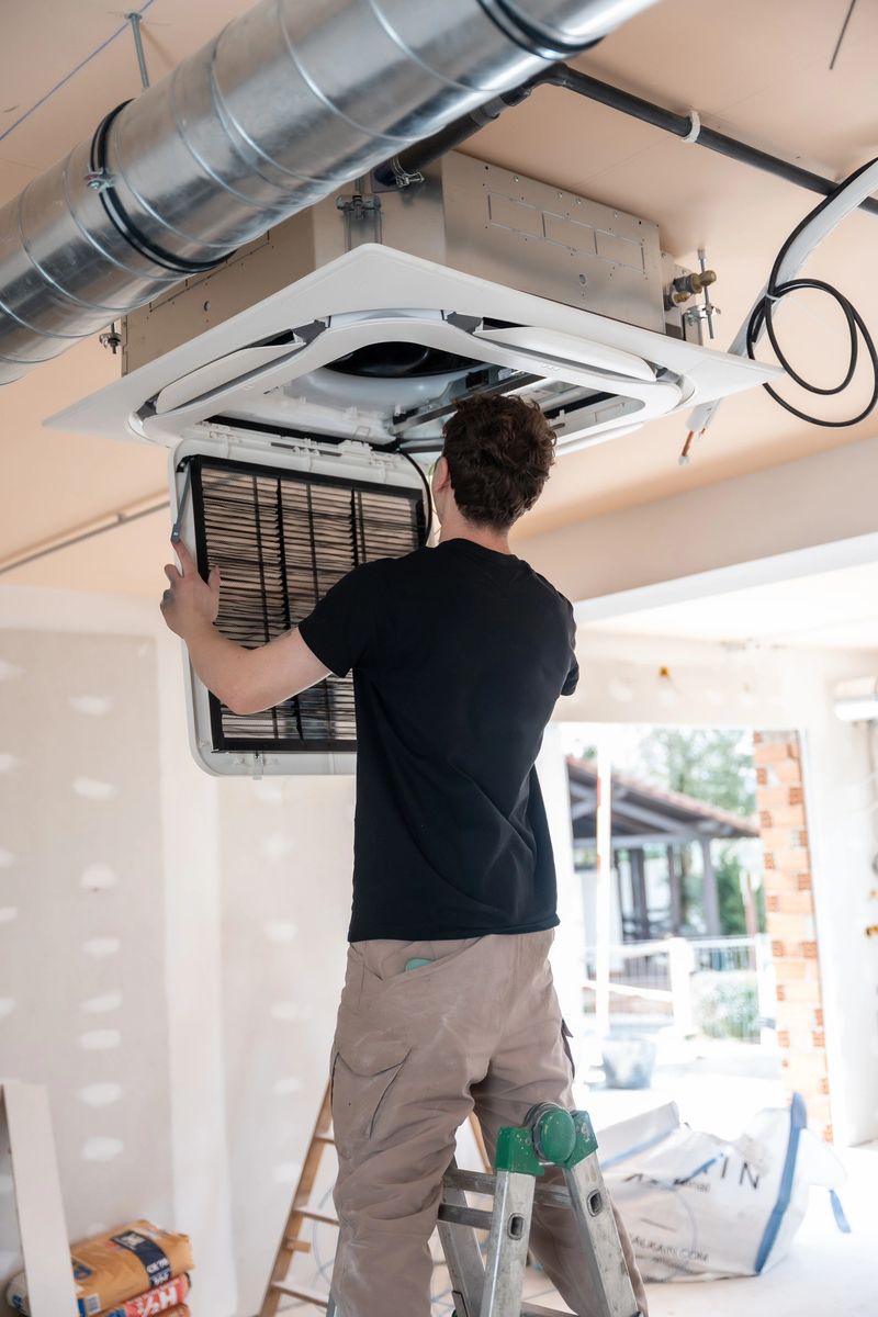 Professional hvac technician installing a modern cassette air conditioning unit into a new building's ceiling, performing essential construction work for climate control