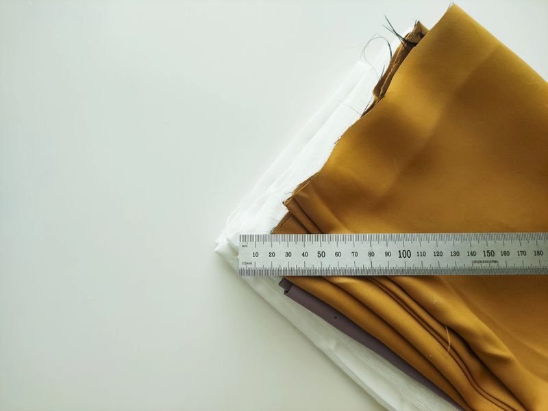 Warm mustard and crisp white fabric swatches neatly stacked on a smooth surface, measuring ruler placed across the top, showcasing the rich textures and colors ideal for creative design projects