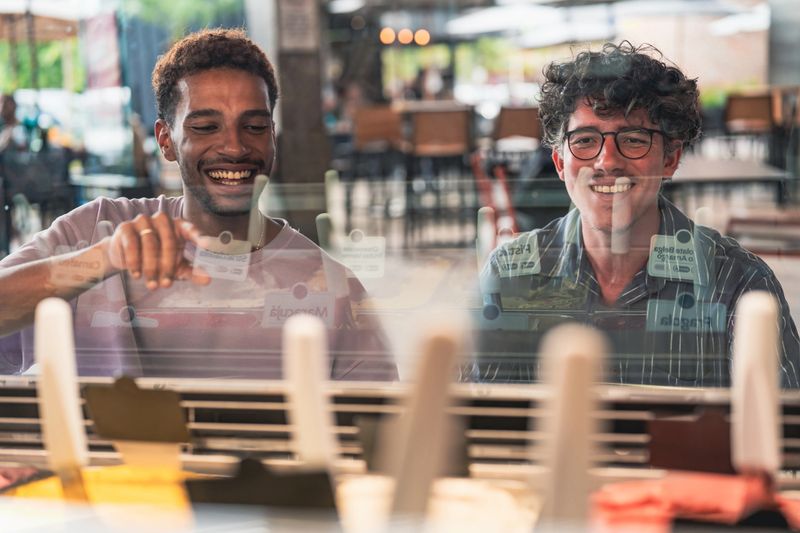 Two friends smiling while choosing ice cream at the counter