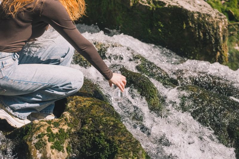 Woman takes fresh drinking water from spring in a bottle