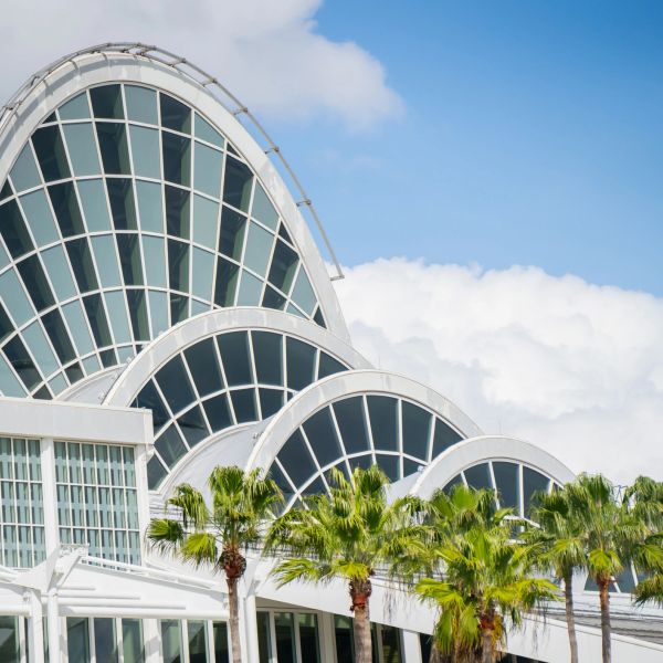 Modern architectural building with curved glass windows and palm trees.