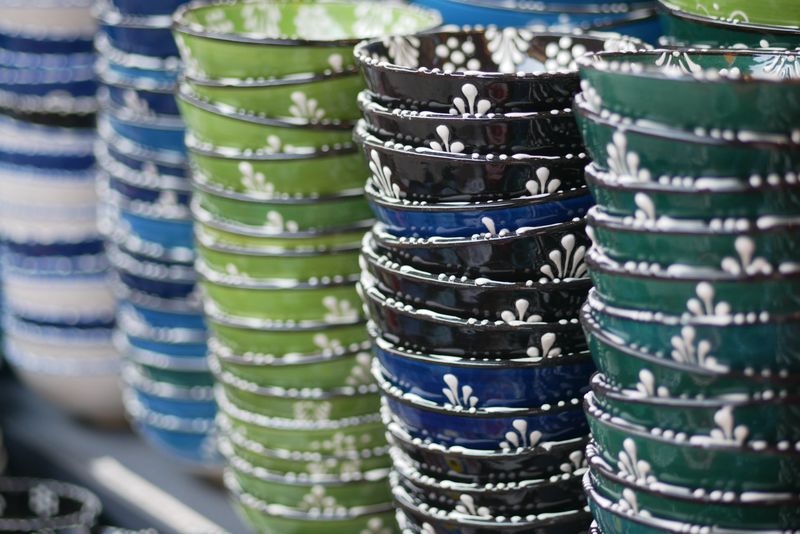 Stacks of vibrant ceramic bowls are arranged for sale at an outdoor market.
