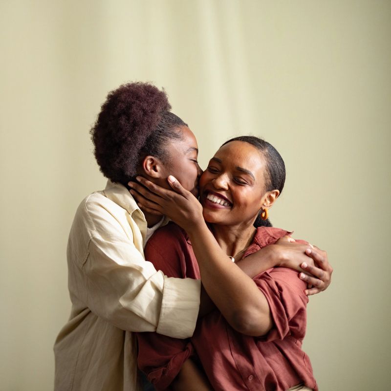 Warm candid portrait of a mother and teenage daughter embracing at home, smiling and sharing a joyful, affectionate moment that highlights family bond, love, comfort, and close connection.