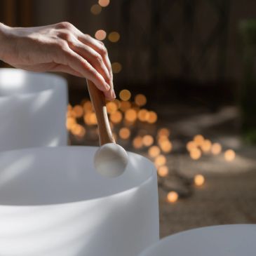 Hand playing a crystal singing bowl with a mallet.