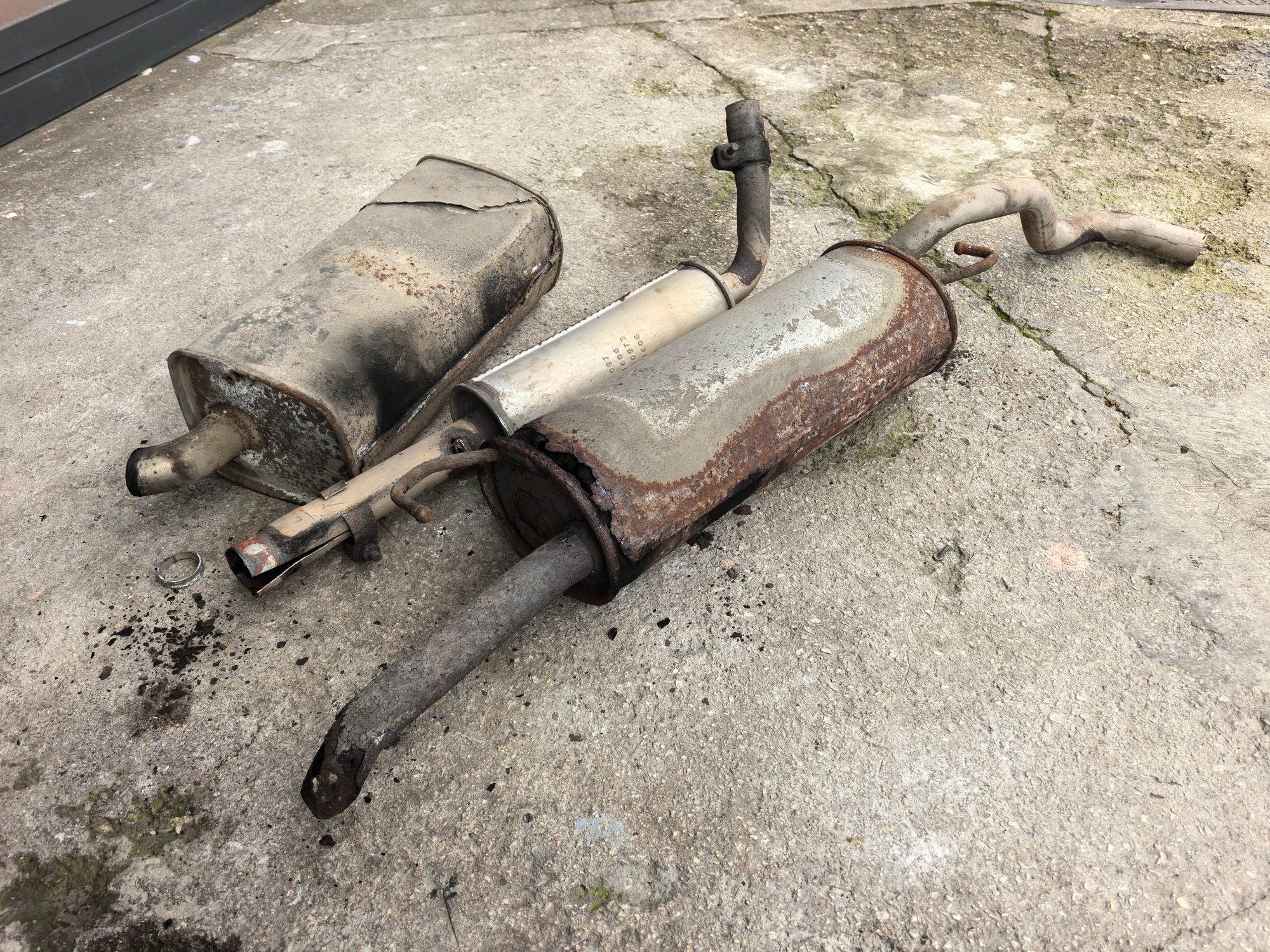 Automotive Repair Costs And Vehicle Maintenance Close Up Of Severely Rusted And Damaged Car Exhaust Systems On Concrete Representing Car Ownership Expenses. High quality photo