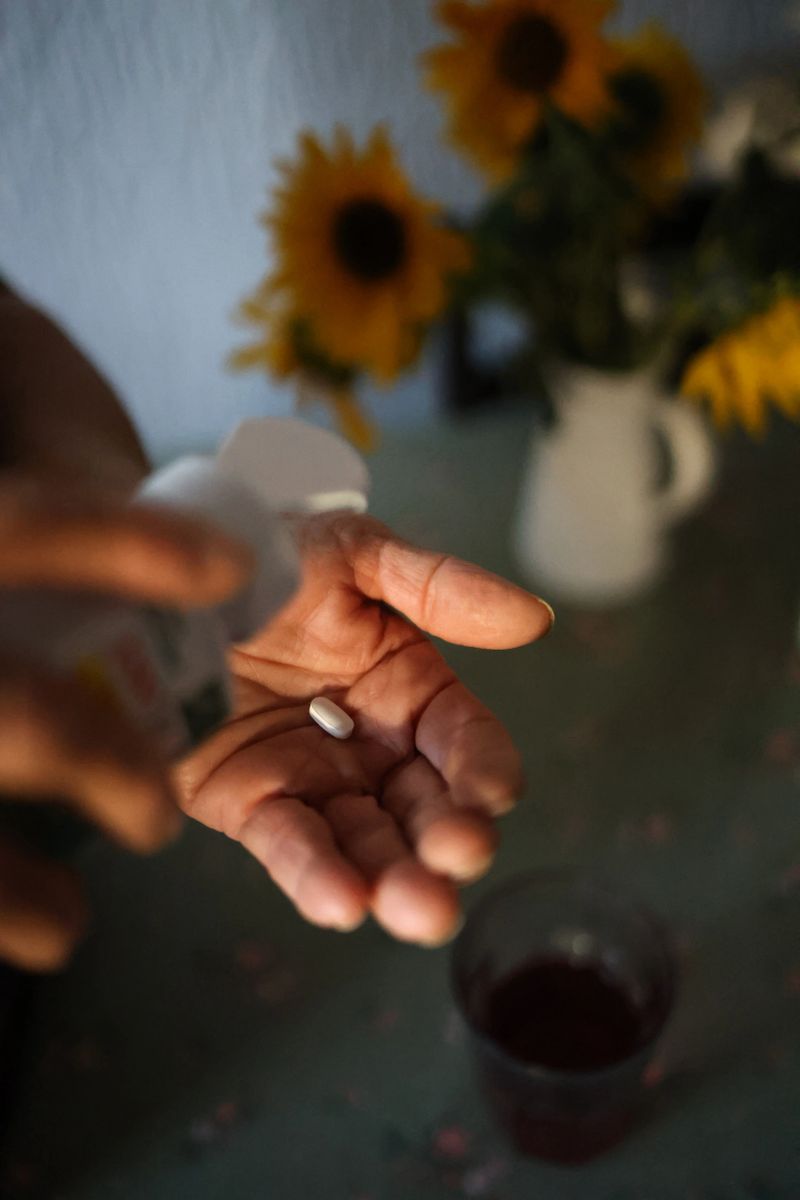 Composition showing a female hands about to take a vitamin with a glass of water, represanting balance, energy and wellbeing