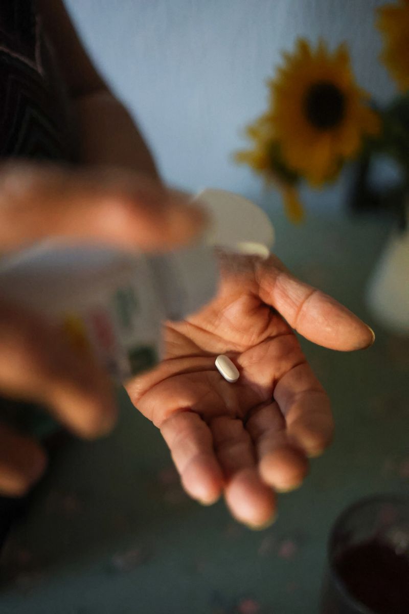 Close-up of female hands holding and pouring collagen supplement pills from the medicine bottle, represanting skincare, beauty and healthy lifestyle.