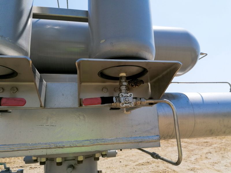 Close up of industrial gas valve and pipeline equipment installed on a metal structure at an energy facility, representing engineering technology and gas infrastructure.