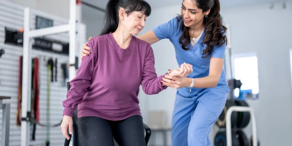 Physical therapist assisting elderly woman with arm movement.