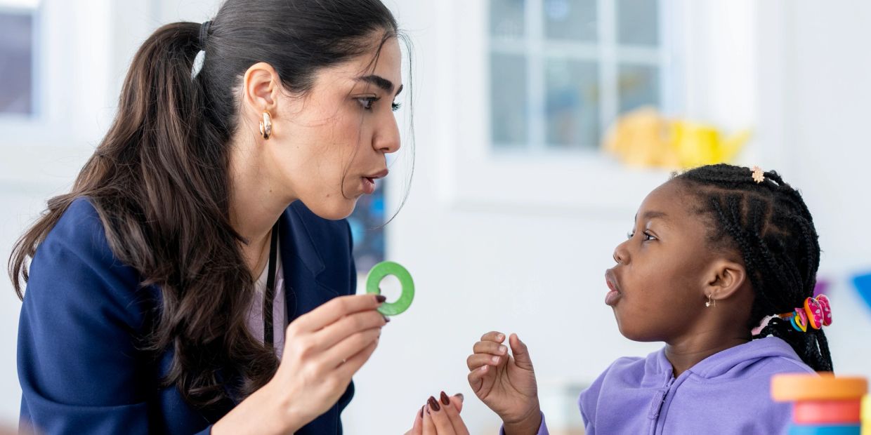 Teacher and child practicing speech with visual aid.