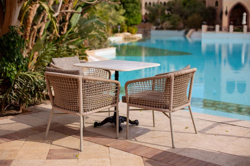 Empty outdoor dining furniture by a swimming pool at a luxury resort