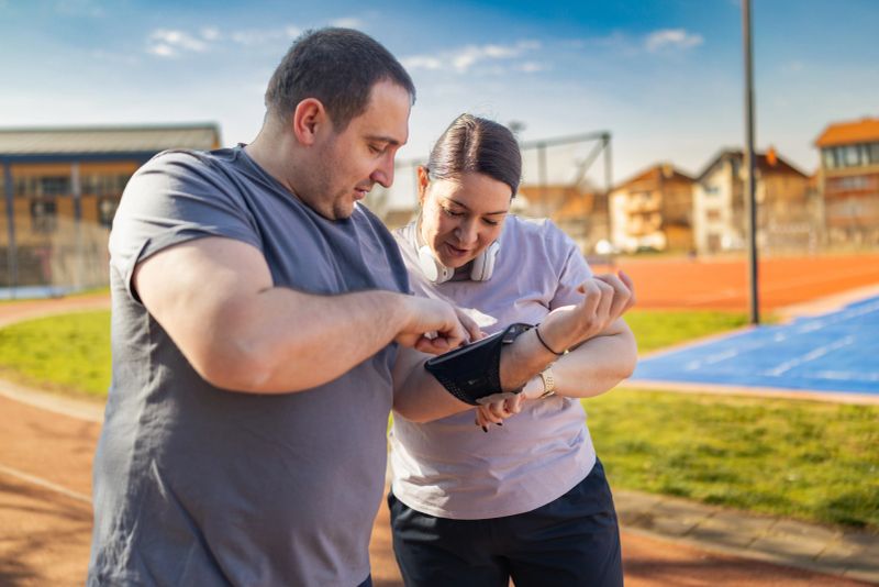 Man helping woman check workout data on her armband phone case during exercise