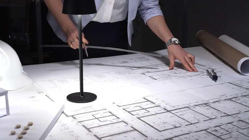 Female architect working on detailed building plans, measuring designs on blueprints with a ruler, conceptualizing new construction. Business and architect people concept