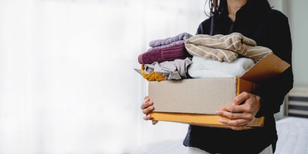 Person holding a box of folded clothes.