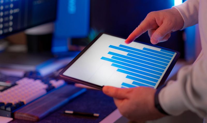 Business data dashboard tablet statistics comparison analysis. Analyst pointing bar chart digital report performance evaluation metrics review data interpretation decision support planning