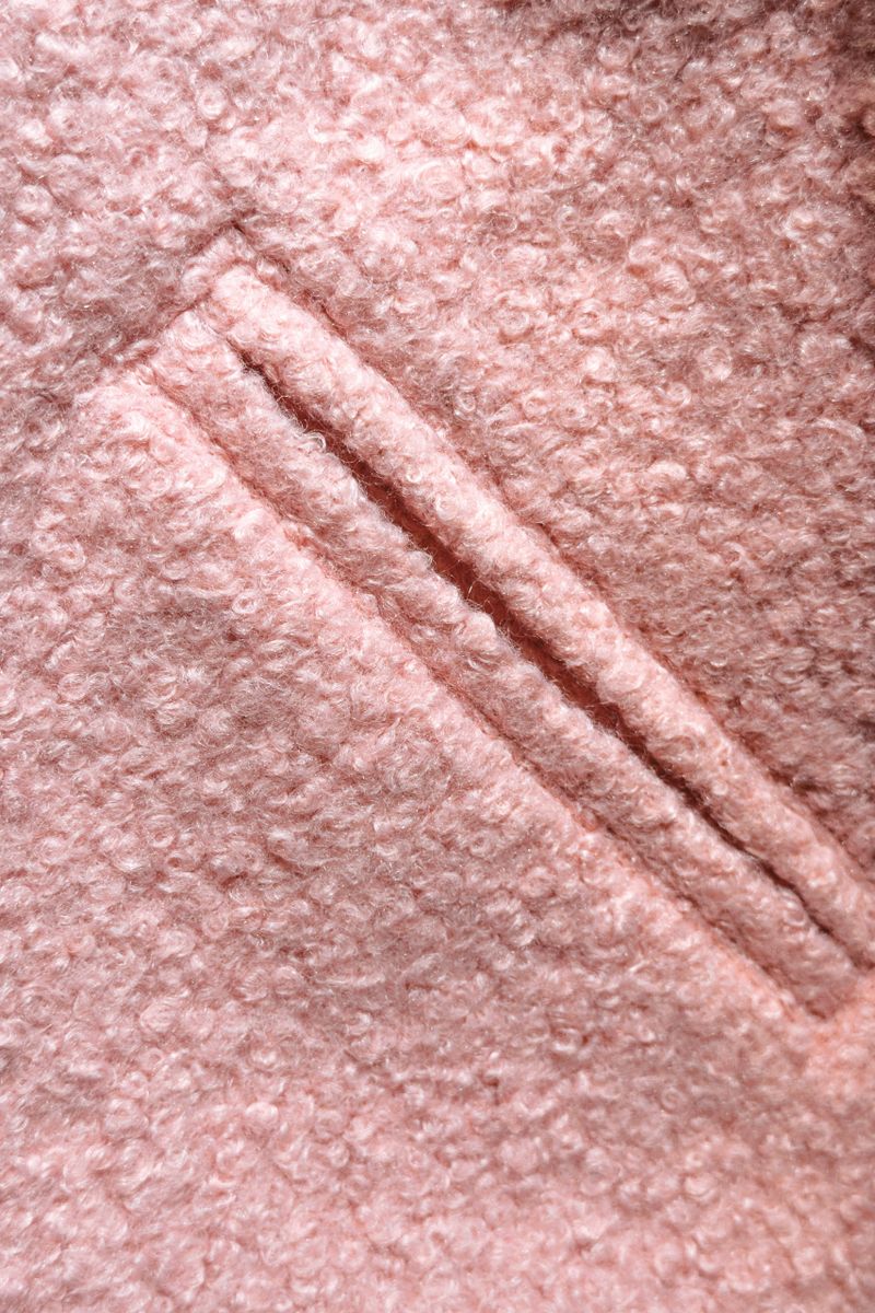 This cozy light pink bouclÃ© fabric displays its intricate loops and diagonal seam detail.