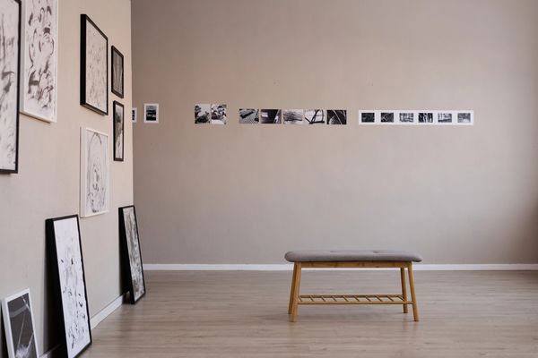 Minimalist art gallery with sketches on walls and a wooden bench.