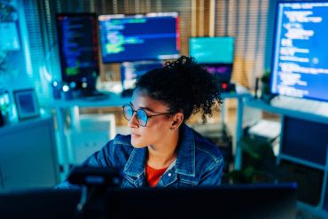Focused woman coding in a tech workspace.
