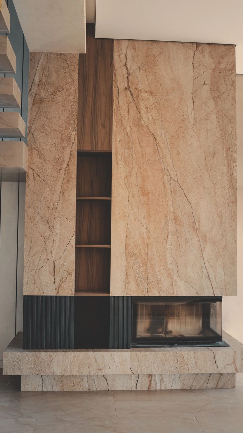A contemporary living space showcases a striking fireplace design combining natural marble, warm wood, and minimalist shelving for a luxurious ambiance