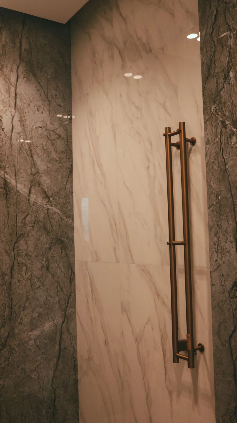 A contemporary bathroom features contrasting marble wall panels and a sleek bronze towel rack, creating a luxurious and functional space