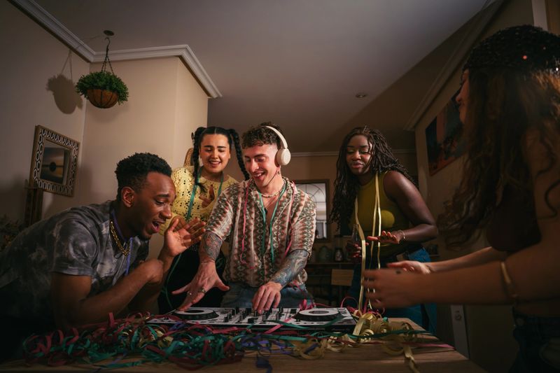 Gen z friends enjoying a home party, dj spinning tracks for friends dancing and celebrating lifestyle with music