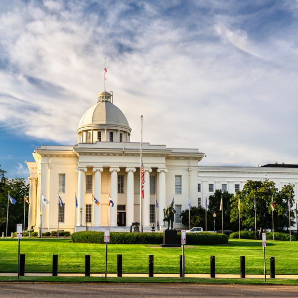 Historic white capitol building with a dome under a blue sky.