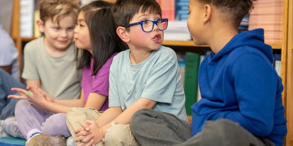 Children sitting and talking together in a classroom setting.