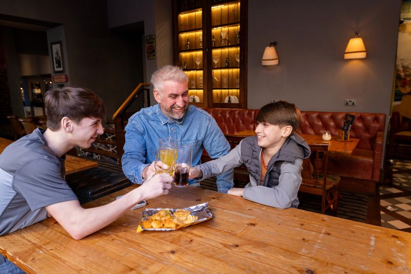 Families enjoying hearty meals and drinks while watching sports at Oakwood pub.