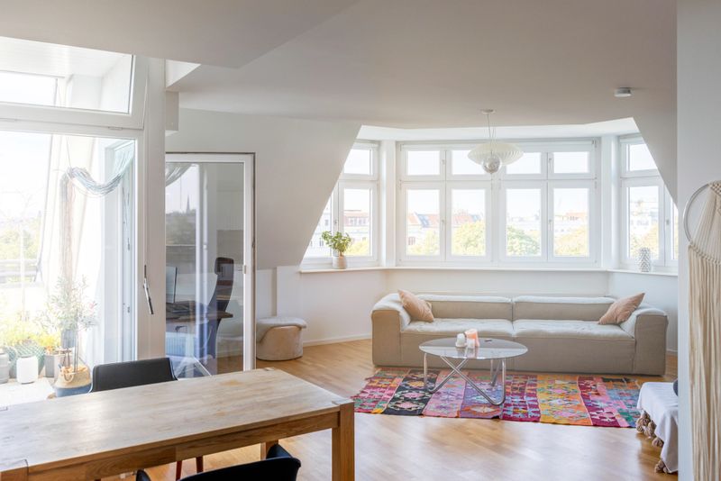 Spacious home apartment living room with large windows, comfortable sofa, and dining area, creating a cozy family atmosphere.