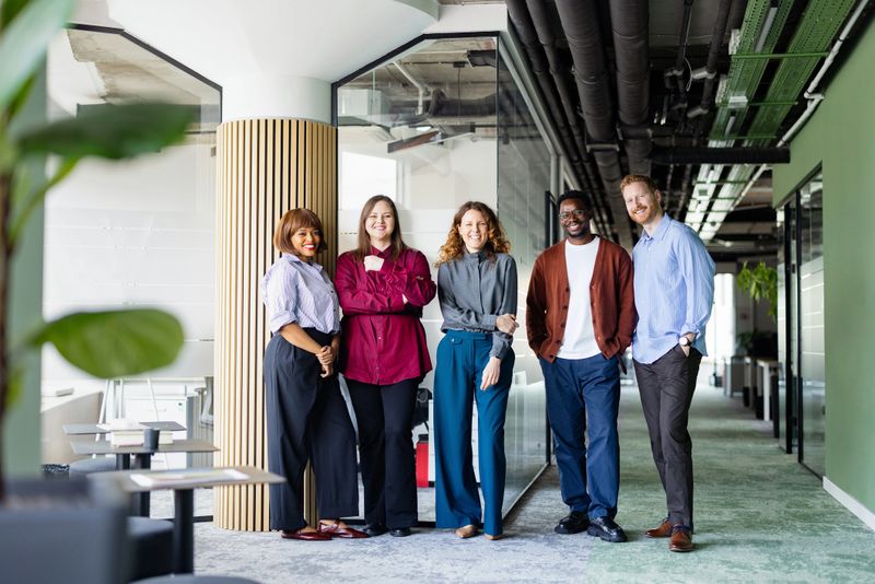 Friendly, diverse business team of colleagues smiling and standing together in a modern office space.