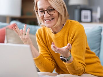 Woman video chatting happily on laptop.
