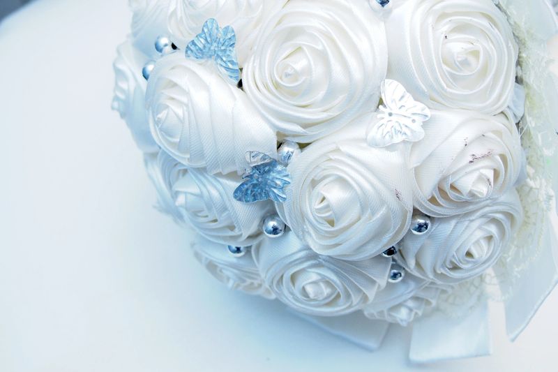 handcrafted wedding brooch bouquet. Instead of real flowers, it is composed of meticulously folded cream or ivory satin ribbons shaped into roses.