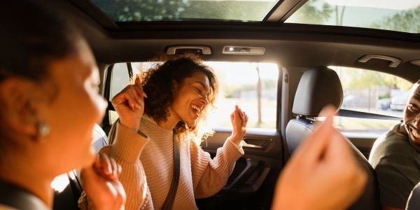 Friends enjoying music and dancing in a car.