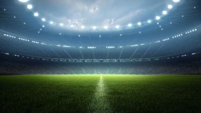 Illuminated empty soccer stadium field at night.
