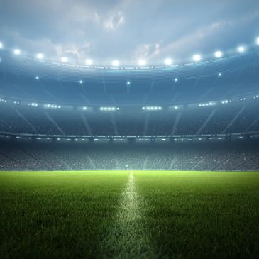 Empty illuminated football stadium at night.