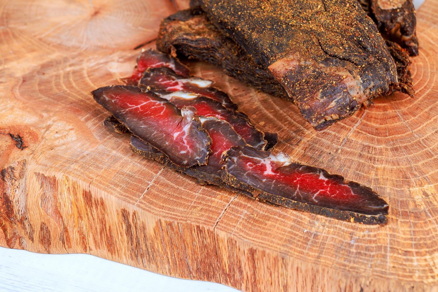 Fresh hand-cut beef jerky sliced on a rustic wooden board.