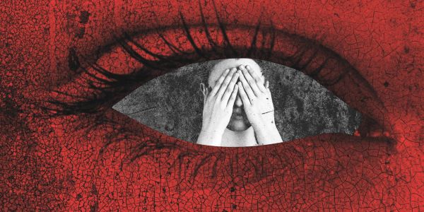 Surreal red eye with person covering face inside the pupil.