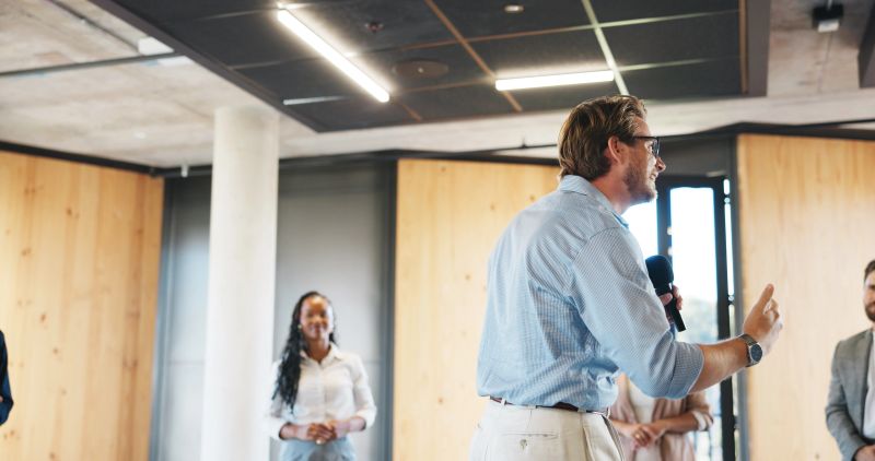 Business, workshop or man in circle with mic, training or expo in skills development. Smile, group of people at corporate seminar with speech, engagement or empowerment for professional growth