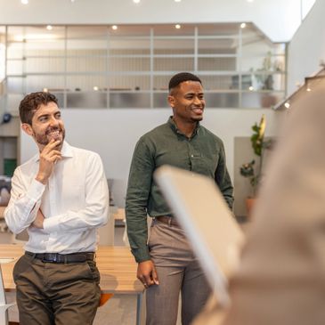 Two men attentively listening and smiling in a modern office setting.