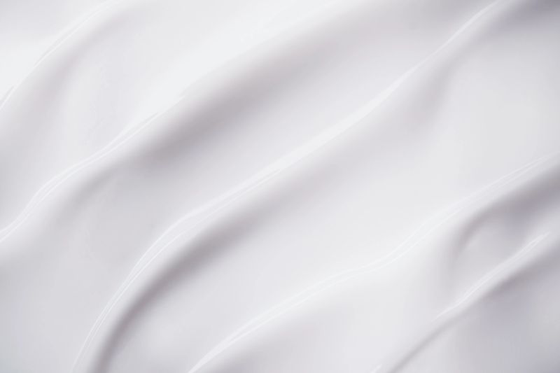 Smooth white cream texture forming elegant flowing waves and swirls.