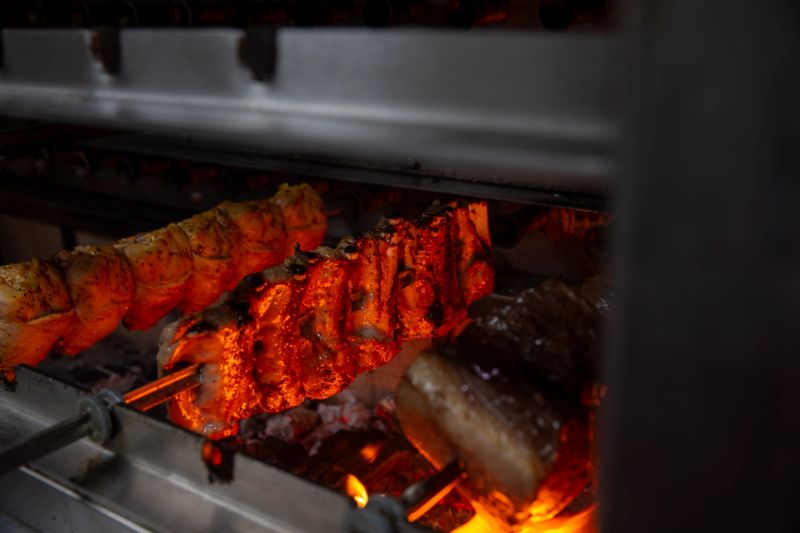 variety of meats on skewers cooking in a rotisserie