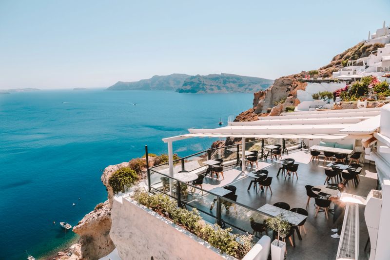 Cliffside seafront restaurant at luxury hotel in Santorini Oia white village on sunny day overlooking aegean sea caldera