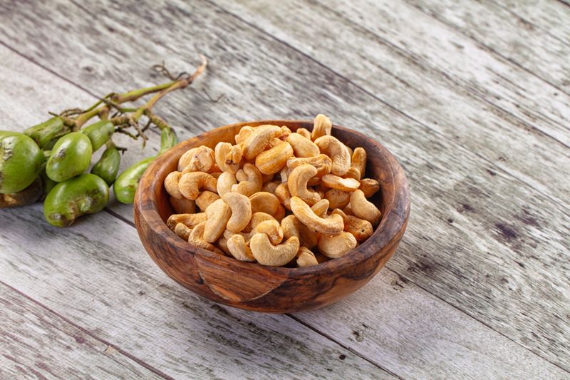 A bowl of golden roasted cashew nuts on a rustic wooden background.