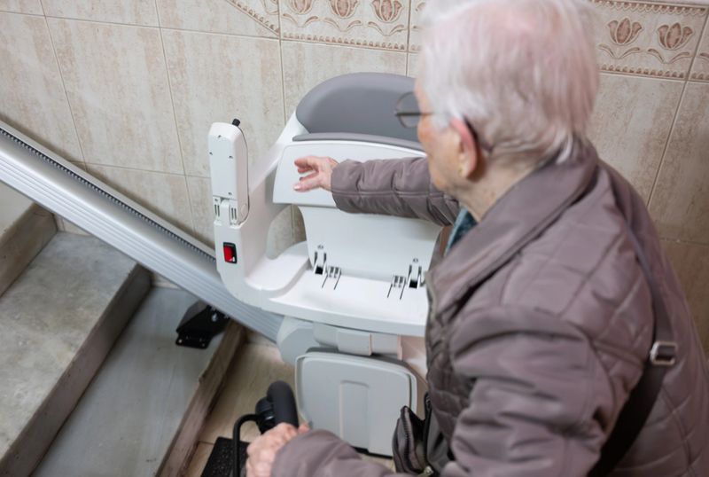 Senior woman is operating a modern stairlift, providing independence and improving mobility for elderly individuals navigating residential stairs safely and comfortably
